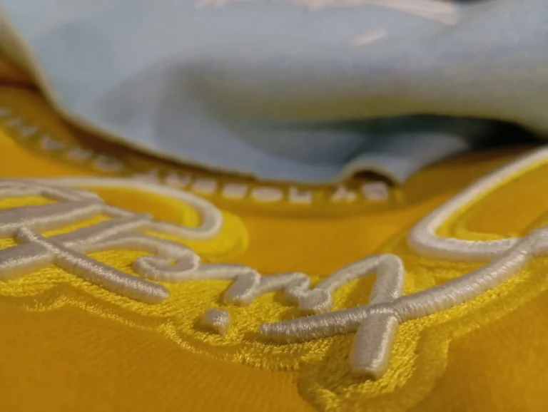 Close-up of 3D script embroidery on a yellow hoodie – made by Naxon Sports