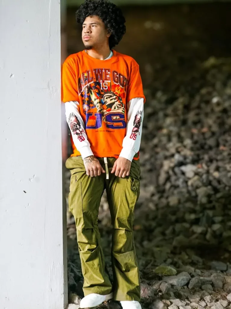 Custom orange graphic t-shirt layered over long sleeves with olive cargo pants – made by Naxon Sports