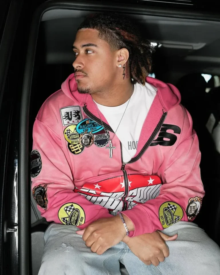Custom pink racing jacket with patches worn with denim shorts – made by Naxon Sports