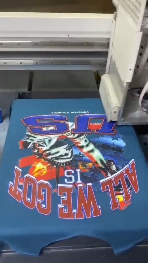 DTG printer printing a full-colour graphic directly onto a blue t-shirt at Naxon Sports factory in Sialkot