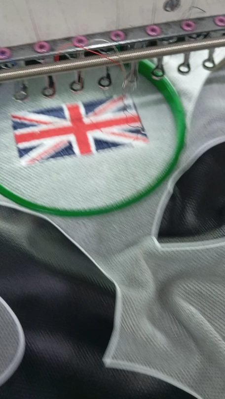 Embroidery machine stitching a Union Jack flag badge on fabric at Naxon Sports factory in Sialkot